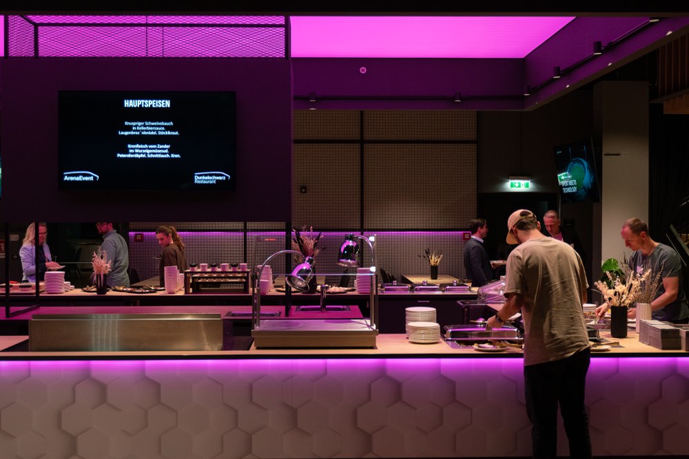 Ausgabe der Hauptspeisen im pink beleuchteten Arena-Restaurant